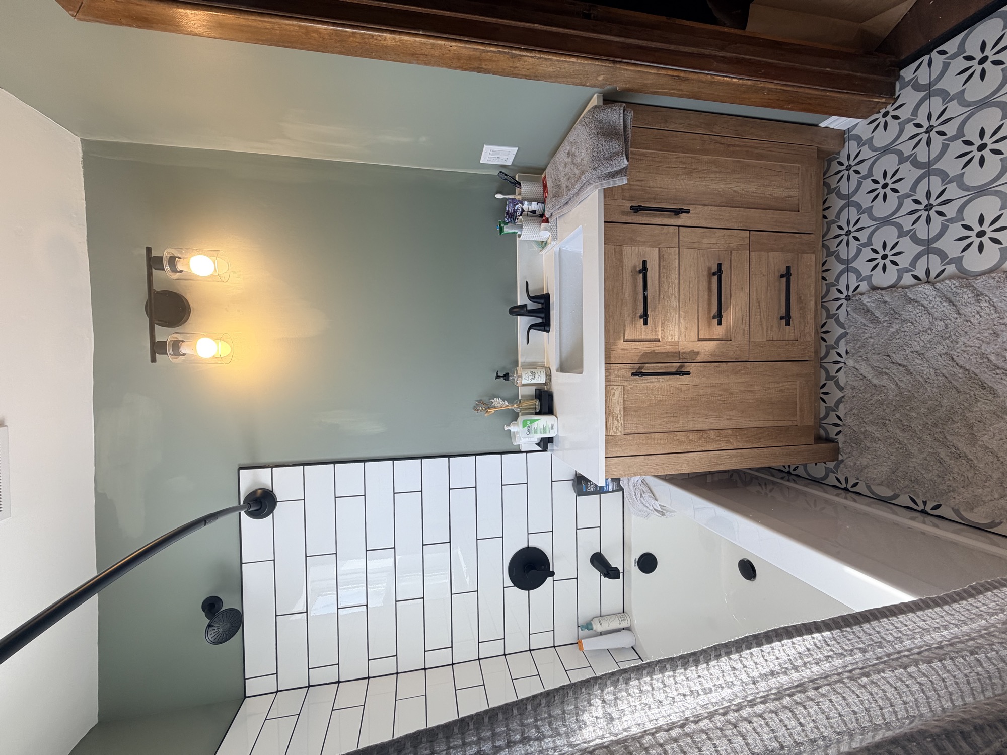 Updated bathroom with tiled tub surround and wood vanity.